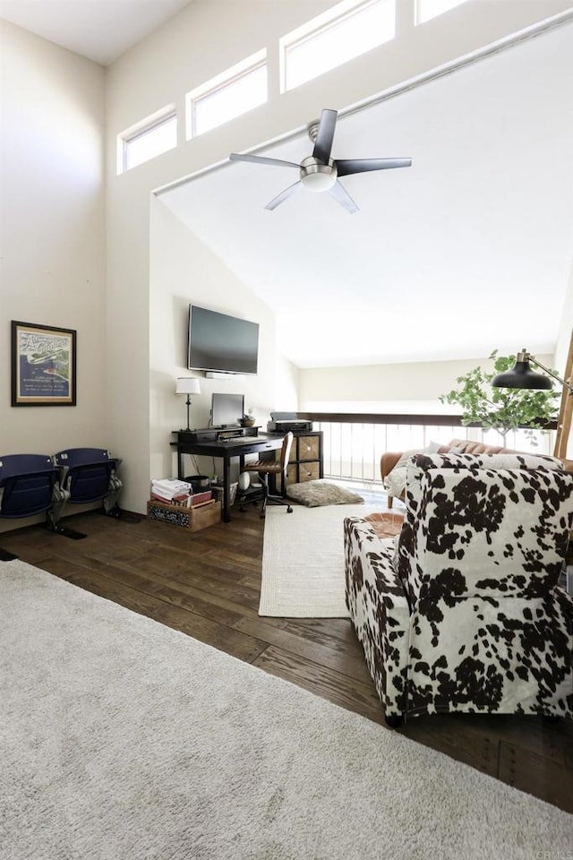 living area with a wealth of natural light, ceiling fan, a towering ceiling, and wood finished floors