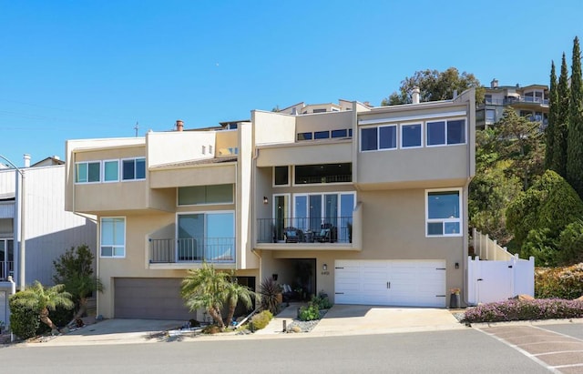 view of front of property with an attached garage, fence, driveway, and stucco siding