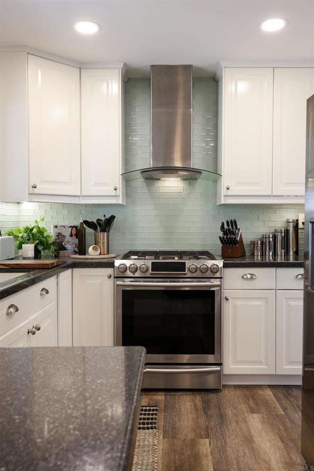 kitchen with tasteful backsplash, dark wood-type flooring, wall chimney range hood, white cabinets, and stainless steel gas range