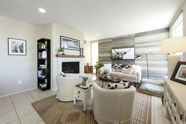 living room featuring light tile patterned floors, recessed lighting, a tile fireplace, and an accent wall