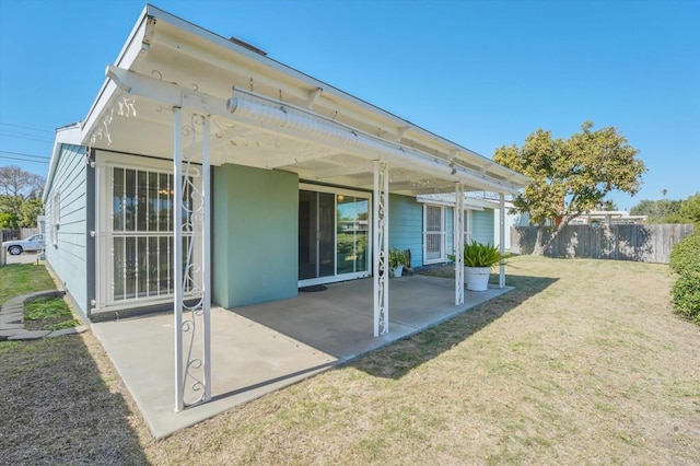 rear view of house featuring a patio area, a lawn, and fence