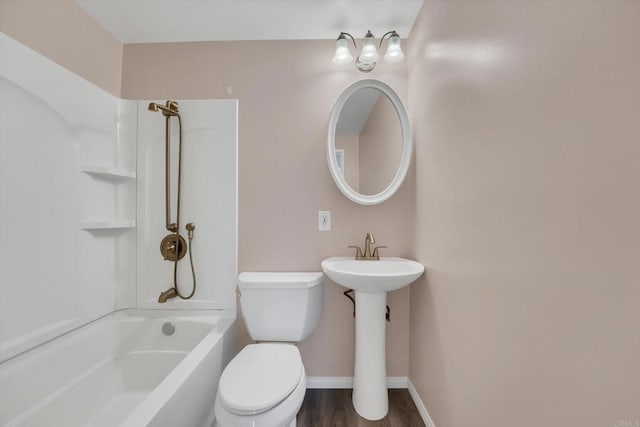 bathroom featuring baseboards, shower / washtub combination, toilet, wood finished floors, and a sink