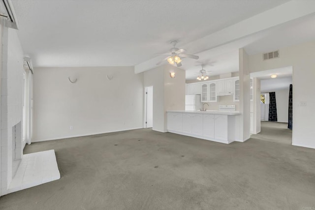 unfurnished living room with visible vents, ceiling fan, carpet floors, a fireplace, and a sink