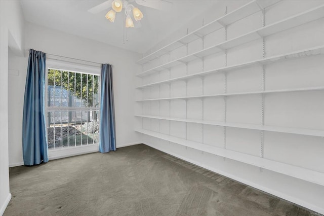 empty room featuring carpet flooring, built in shelves, and ceiling fan