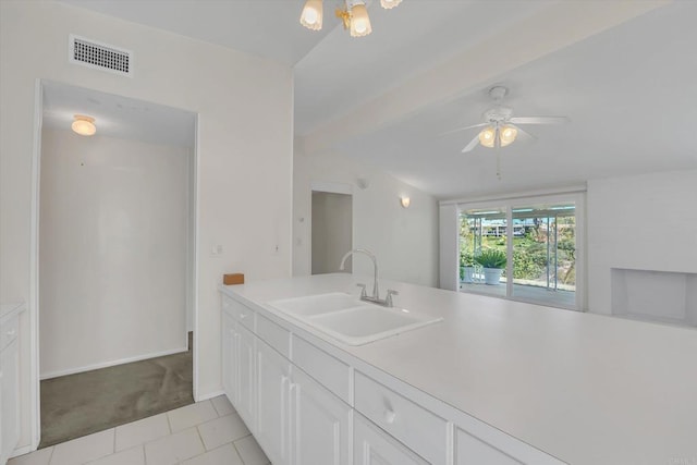 kitchen featuring visible vents, beam ceiling, light carpet, a sink, and light countertops