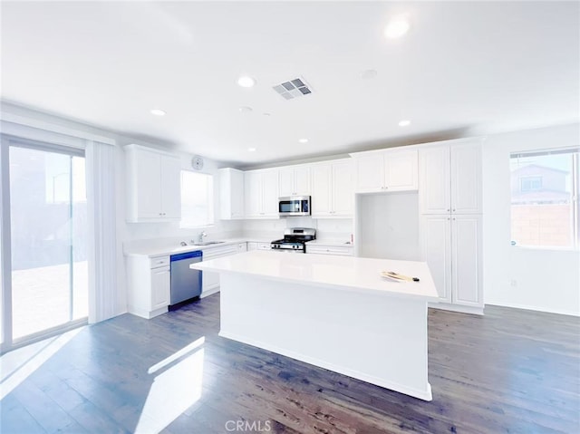 kitchen featuring visible vents, wood finished floors, white cabinets, stainless steel appliances, and a sink