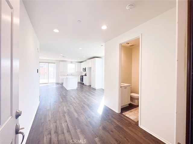 unfurnished living room with dark wood finished floors, recessed lighting, and baseboards