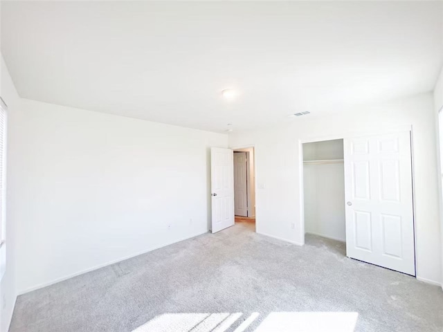 unfurnished bedroom featuring a closet and light carpet