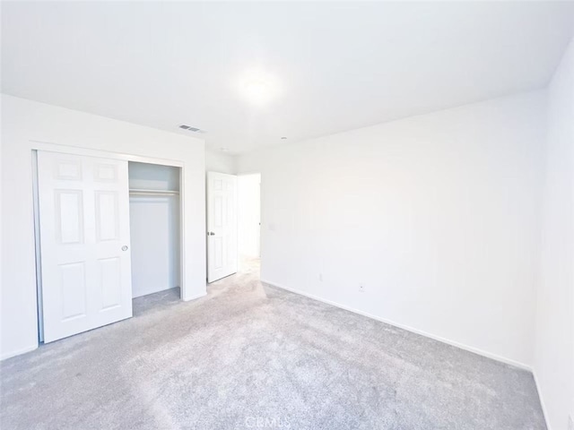 unfurnished bedroom with a closet, visible vents, and carpet floors