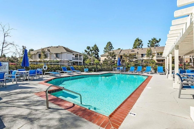 community pool with a patio, fence, and a residential view