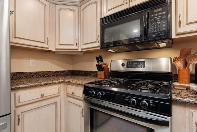 kitchen with dark stone counters, cream cabinetry, gas stove, and black microwave