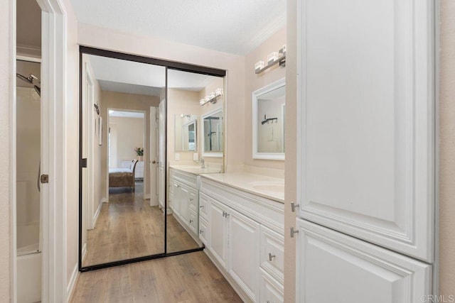 ensuite bathroom featuring a sink, ensuite bathroom, wood finished floors, and double vanity