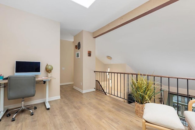 office space featuring lofted ceiling with beams, baseboards, and wood finished floors