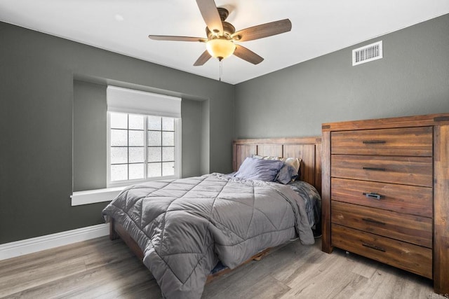 bedroom with visible vents, baseboards, wood finished floors, and a ceiling fan