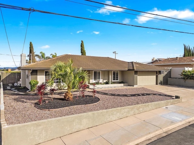 ranch-style home featuring concrete driveway, a tiled roof, a garage, and stucco siding