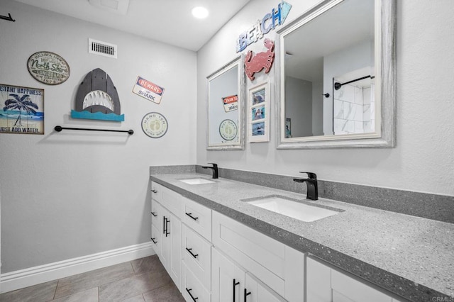 bathroom featuring double vanity, visible vents, baseboards, and a sink