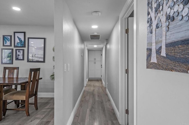 hallway with visible vents, recessed lighting, baseboards, and wood finished floors