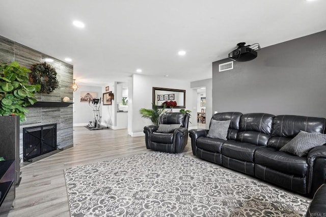 living room featuring wood finished floors, visible vents, baseboards, recessed lighting, and a fireplace