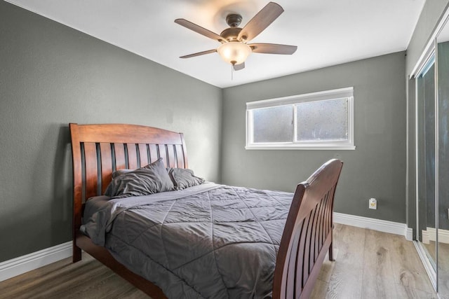 bedroom featuring baseboards, wood finished floors, and a ceiling fan