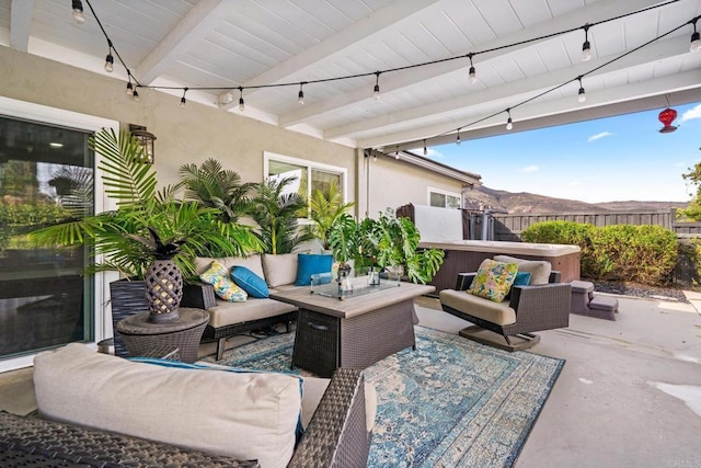 view of patio featuring an outdoor living space, a mountain view, a hot tub, and fence