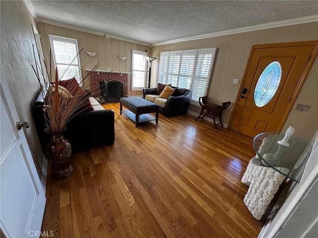 living room featuring a fireplace, a textured ceiling, wood finished floors, and ornamental molding