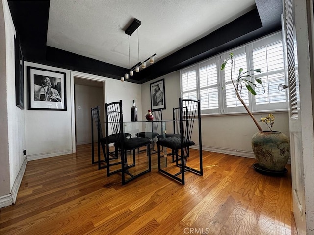 dining area with a textured ceiling, light wood-type flooring, and baseboards