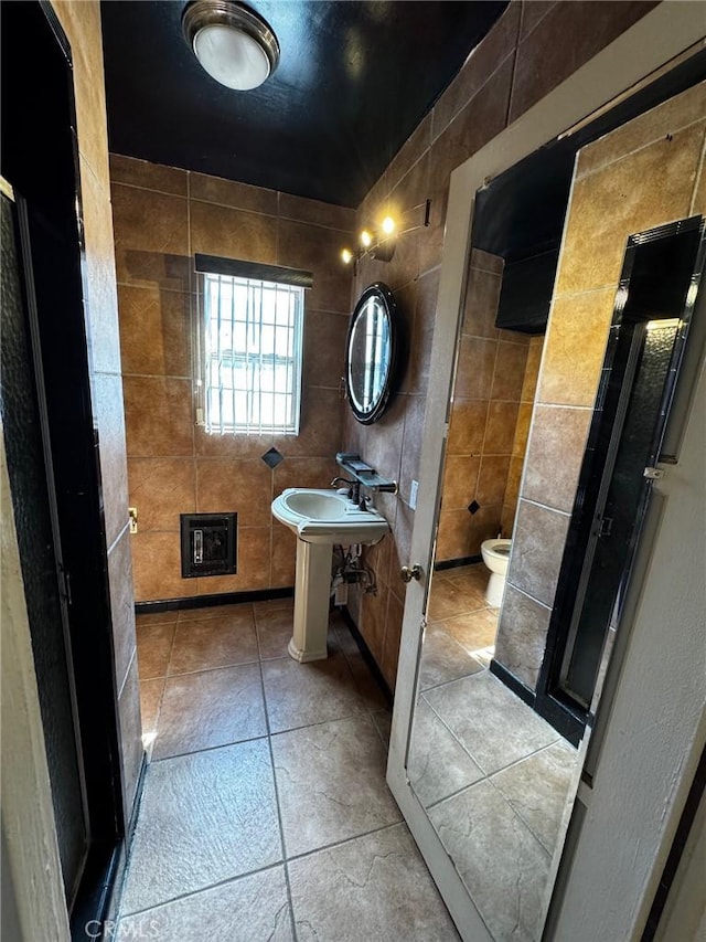 full bathroom with tile walls, toilet, and a stall shower