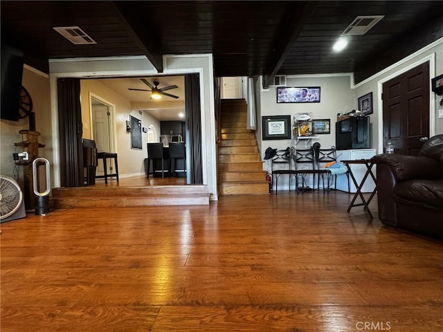 living room featuring stairway, beamed ceiling, visible vents, and wood finished floors