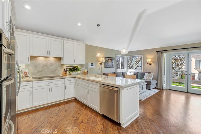 kitchen featuring a sink, stainless steel dishwasher, open floor plan, white cabinets, and black electric stovetop