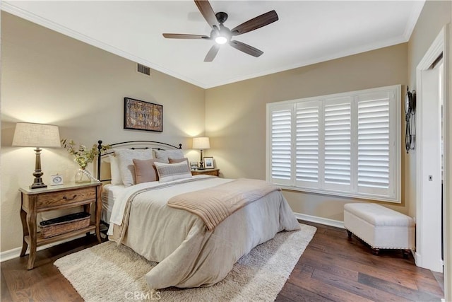 bedroom featuring dark wood finished floors, crown molding, baseboards, and visible vents