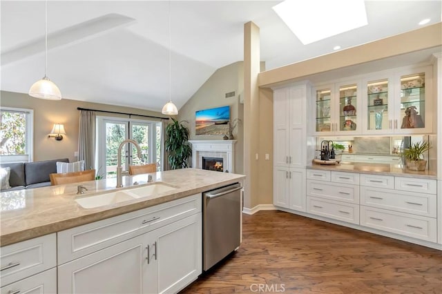 kitchen featuring pendant lighting, a sink, vaulted ceiling with skylight, white cabinets, and dishwasher