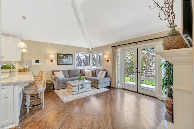 living area with vaulted ceiling with beams, wood finished floors, and french doors