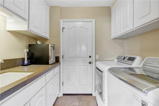 laundry room featuring light tile patterned floors, a sink, cabinet space, and separate washer and dryer