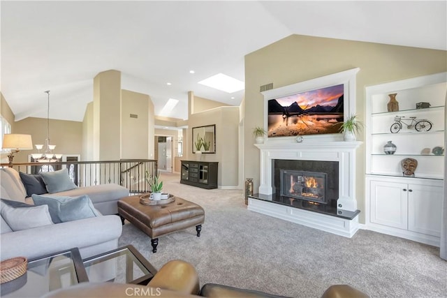 living room featuring a notable chandelier, built in features, a glass covered fireplace, carpet flooring, and vaulted ceiling