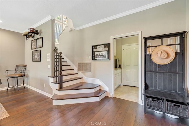 entrance foyer featuring stairway, baseboards, visible vents, ornamental molding, and hardwood / wood-style flooring