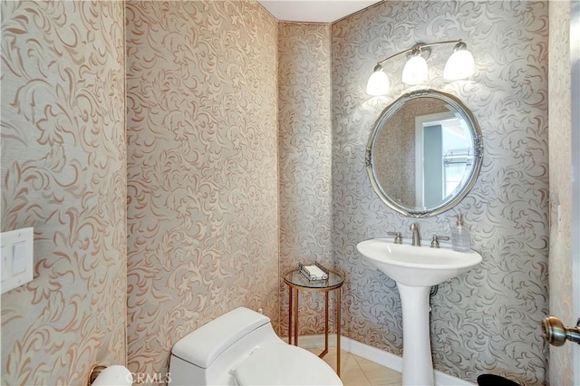 half bath with tile patterned floors, toilet, and wallpapered walls