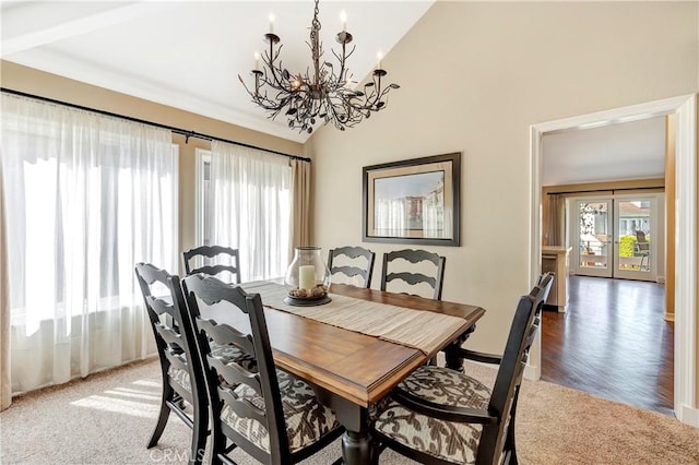 dining area with light carpet, a chandelier, and vaulted ceiling