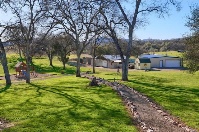 view of community with a garage, a lawn, and playground community