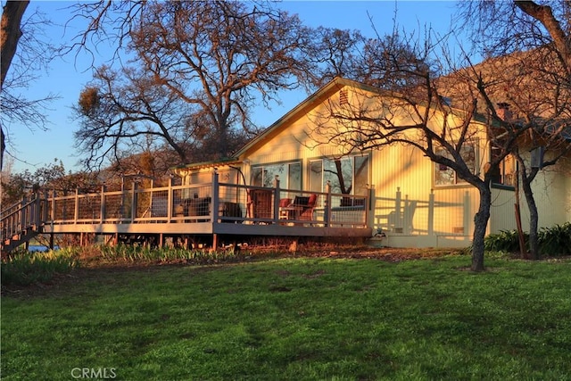 back of property with a wooden deck and a yard