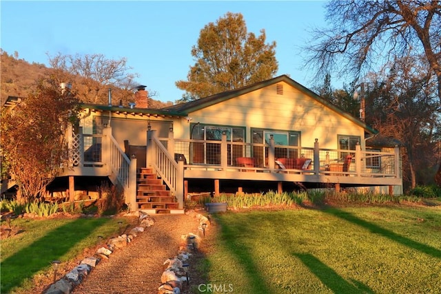 rear view of property featuring a deck, stairway, a yard, and a chimney