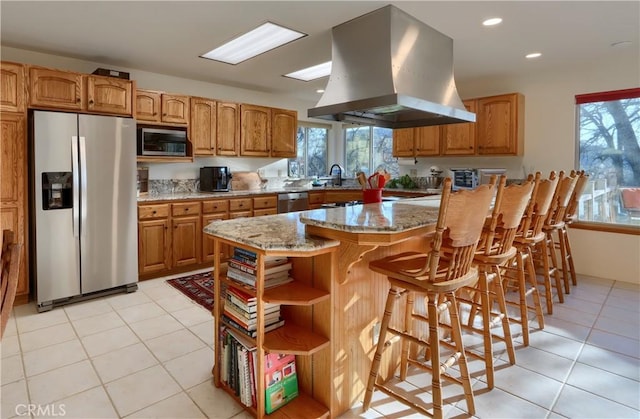 kitchen with light stone countertops, light tile patterned floors, appliances with stainless steel finishes, island range hood, and open shelves