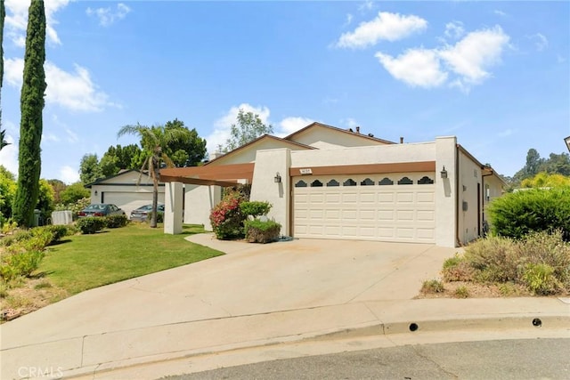 view of front of house featuring stucco siding, an attached garage, driveway, and a front yard