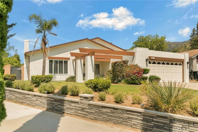 view of front of home with a front yard, driveway, an attached garage, a chimney, and stucco siding