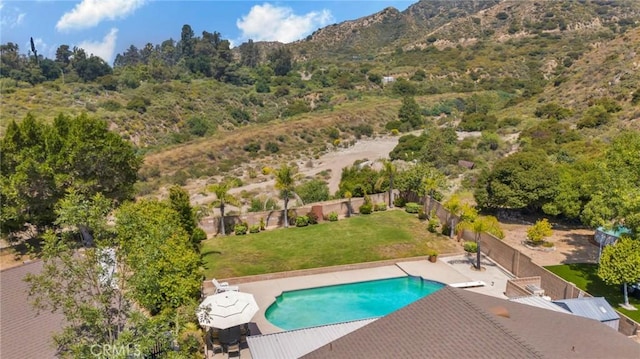 view of pool featuring a lawn, a patio, fence, a mountain view, and a fenced in pool