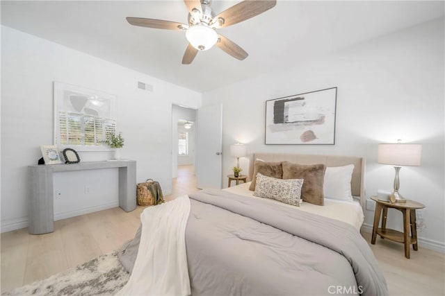 bedroom with visible vents, baseboards, a ceiling fan, and wood finished floors