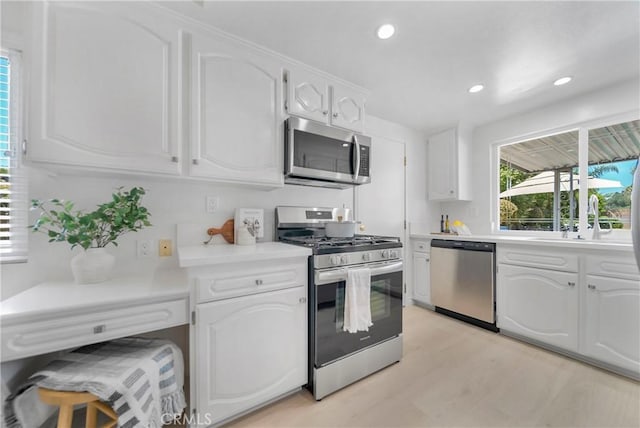 kitchen with light wood-style flooring, recessed lighting, light countertops, white cabinets, and appliances with stainless steel finishes