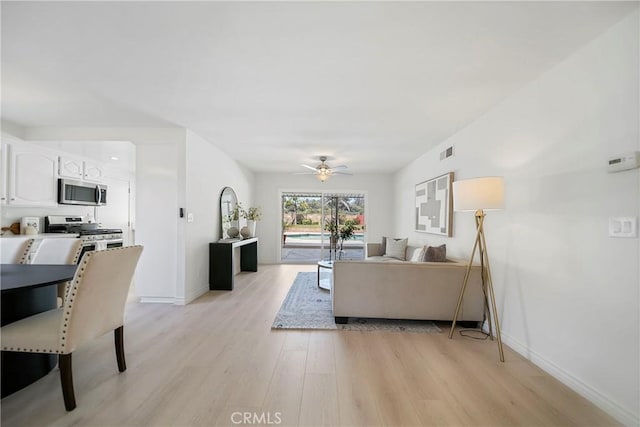 living room featuring visible vents, a ceiling fan, light wood-type flooring, and baseboards