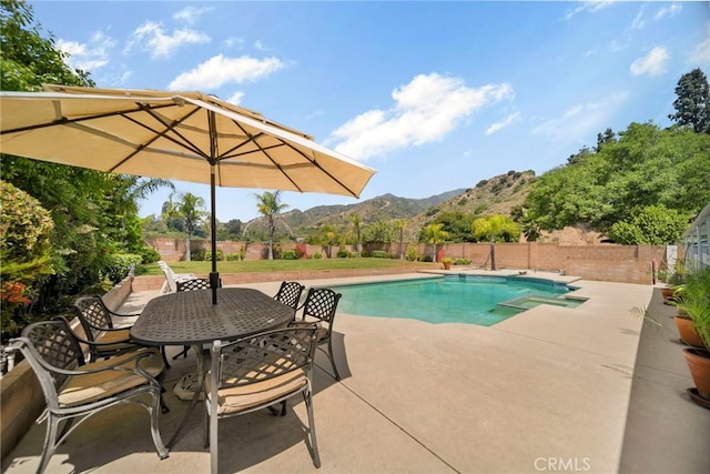 view of pool featuring a patio area, a mountain view, outdoor dining area, and a fenced backyard