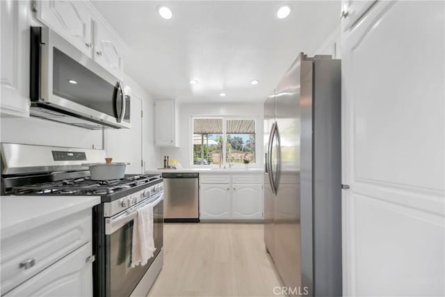 kitchen with light wood-type flooring, white cabinets, stainless steel appliances, and light countertops