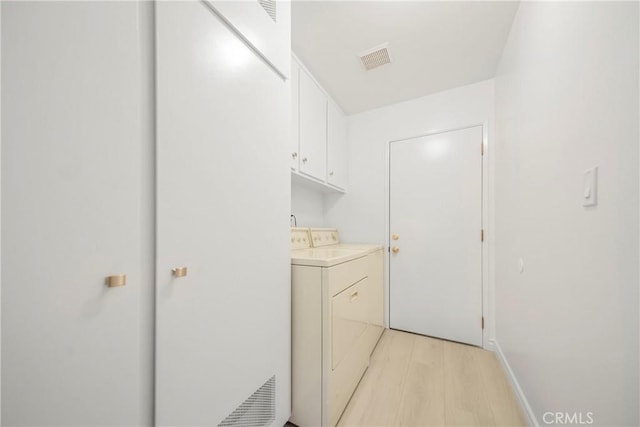 laundry room with cabinet space, visible vents, washing machine and dryer, and light wood-type flooring